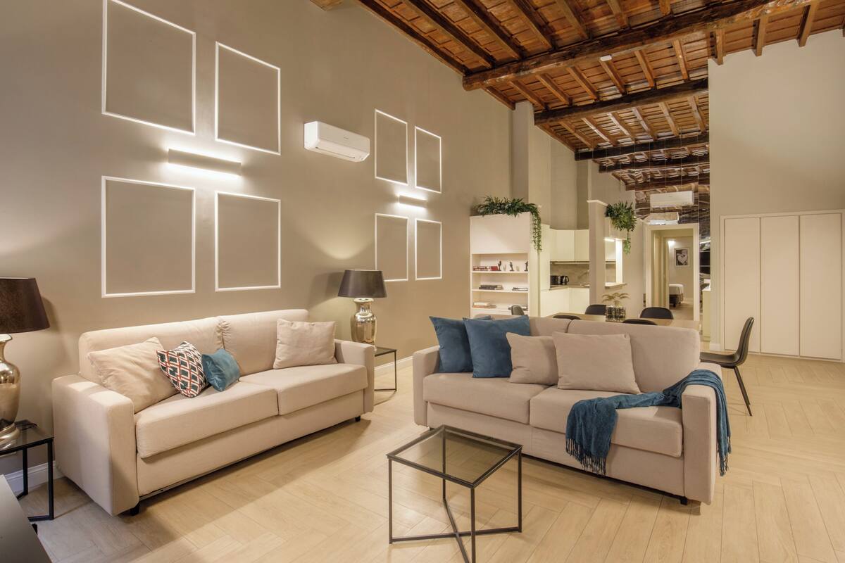A spacious living room with two sofas, a coffee table, and a wooden ceiling.