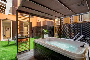 A modern outdoor spa area with a hot tub, wooden deck, and a patterned wall.