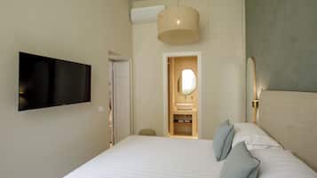 A modern hotel room with a large bed, a television mounted on the wall, a wooden door leading to a bathroom, and a pendant light above the bed.