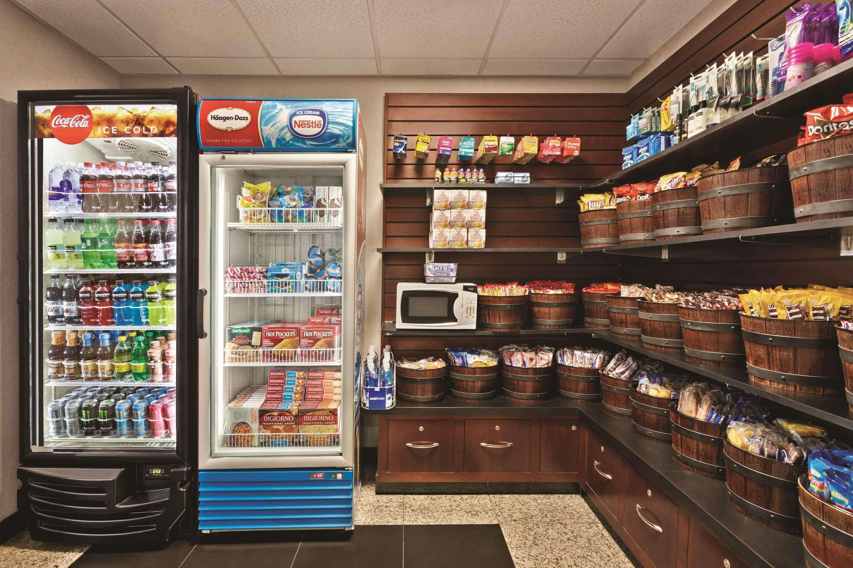 A self-service beverage and snack station with a Coca-Cola cooler, Häagen-Dazs ice cream, and various snacks and condiments.