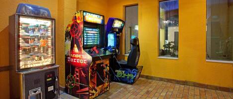 A gaming area with arcade machines, a vending machine, and a brick floor.