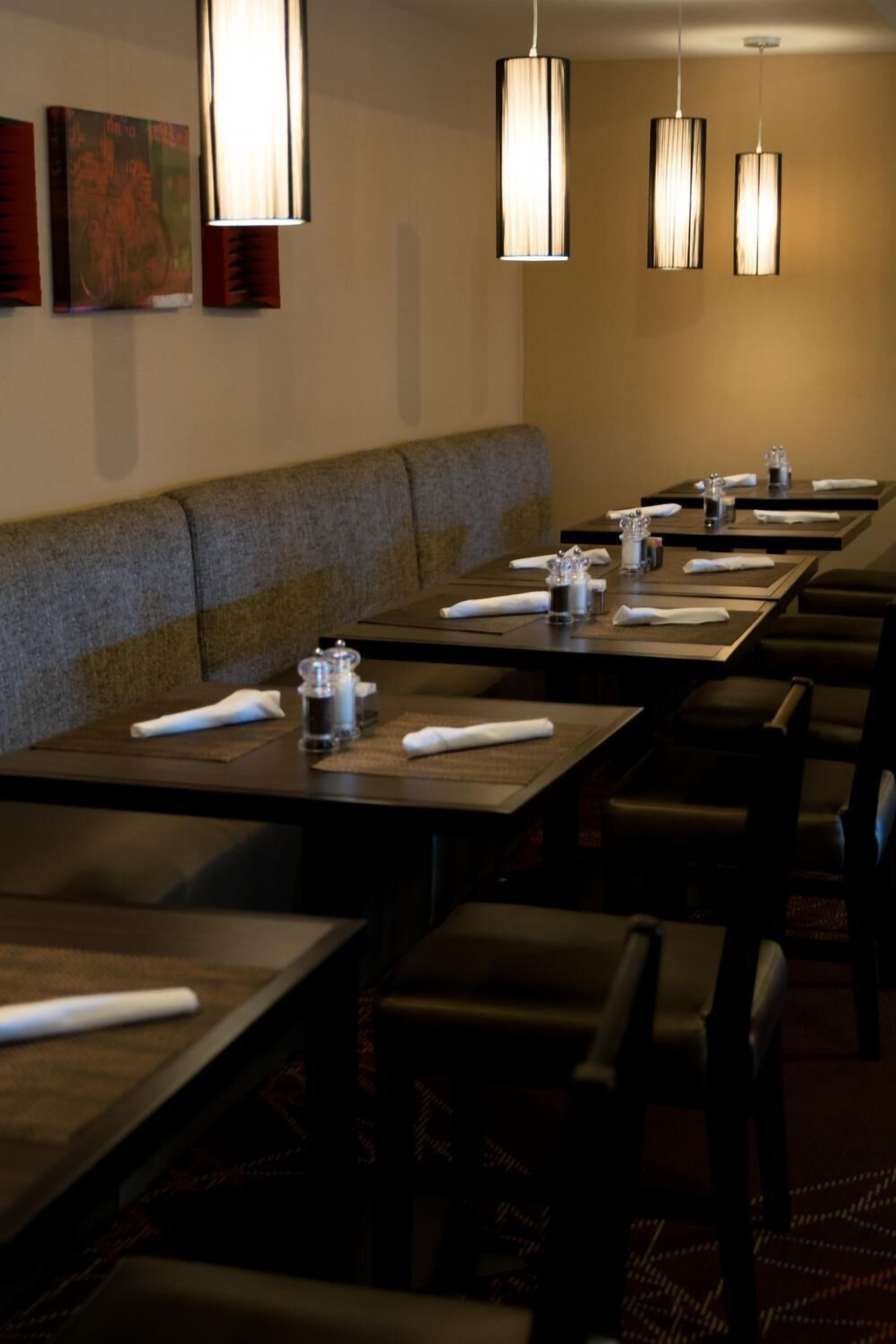 Un restaurante con mesas largas, cabinas acolchadas e iluminación colgante.