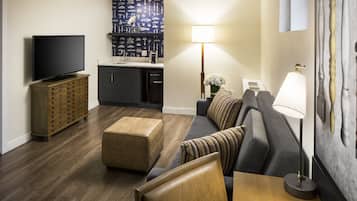 Una sala de estar moderna con televisor de pantalla plana, un sofá, un reposapiés y una mesa de comedor.