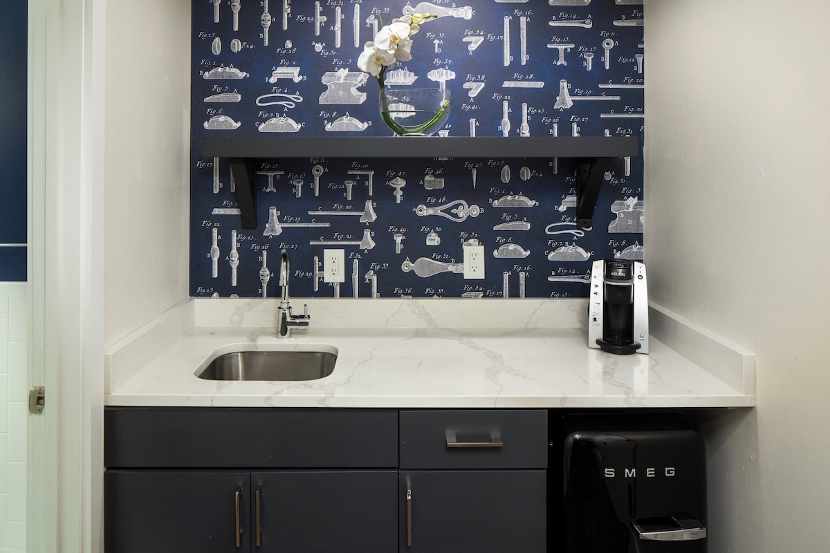 A kitchen with a marble countertop, a sink, and a coffee maker.