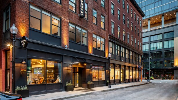 A hotel with a brick facade, large windows, and a modern glass building adjacent to it.