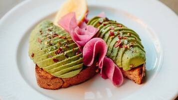 A plate with avocado toast and a slice of lemon.