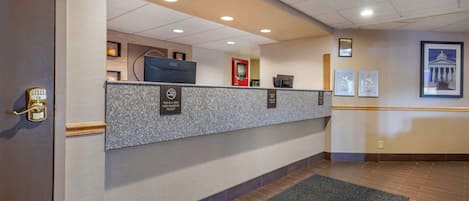 A reception area with a counter, a security keypad, a red emergency phone, and framed certificates on the wall.