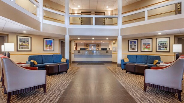 Un hall d’hôtel avec un comptoir d’accueil central, deux canapés et une moquette à motifs.