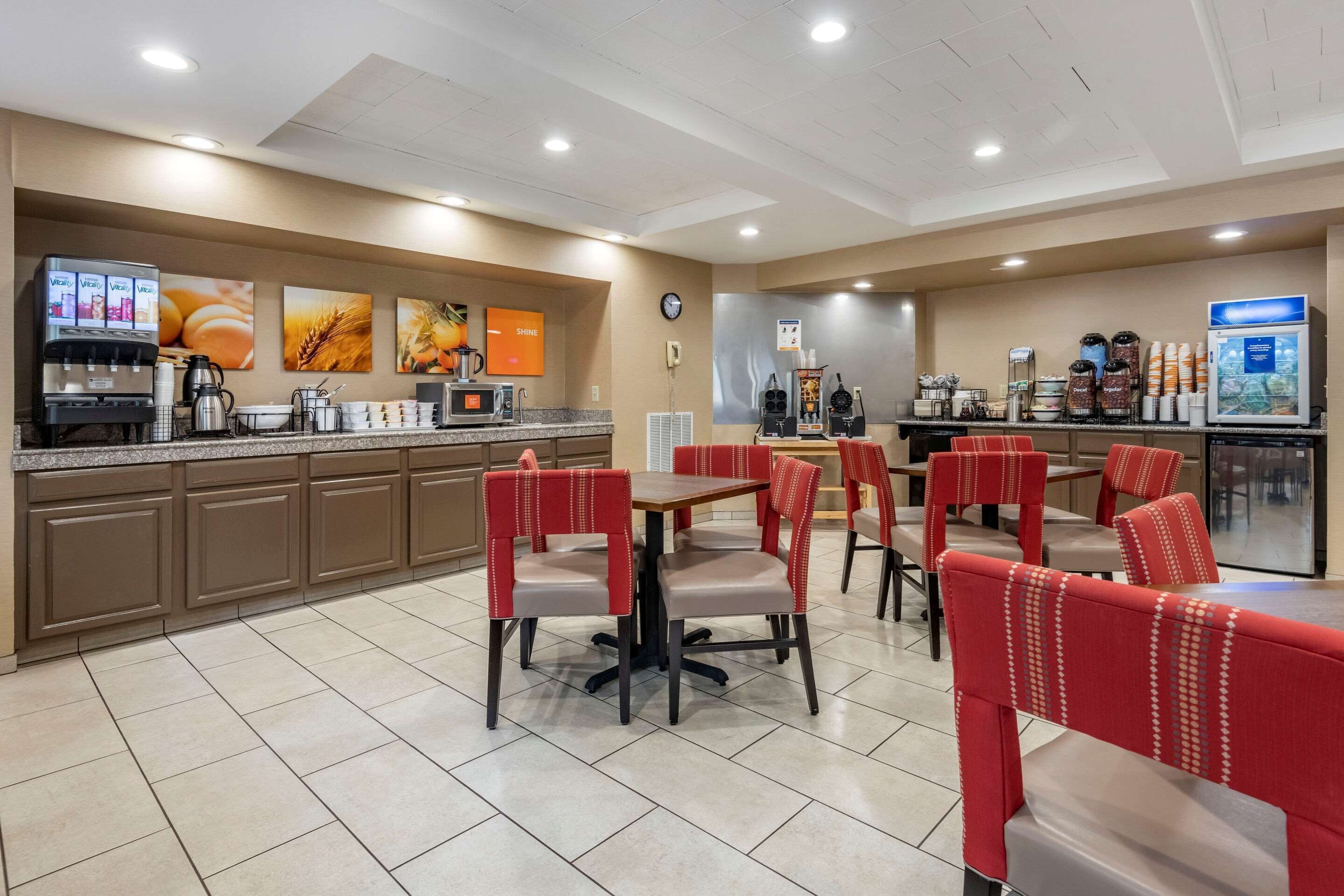 Un espace repas d’hôtel avec des banquettes rouges, un distributeur de café et un buffet.