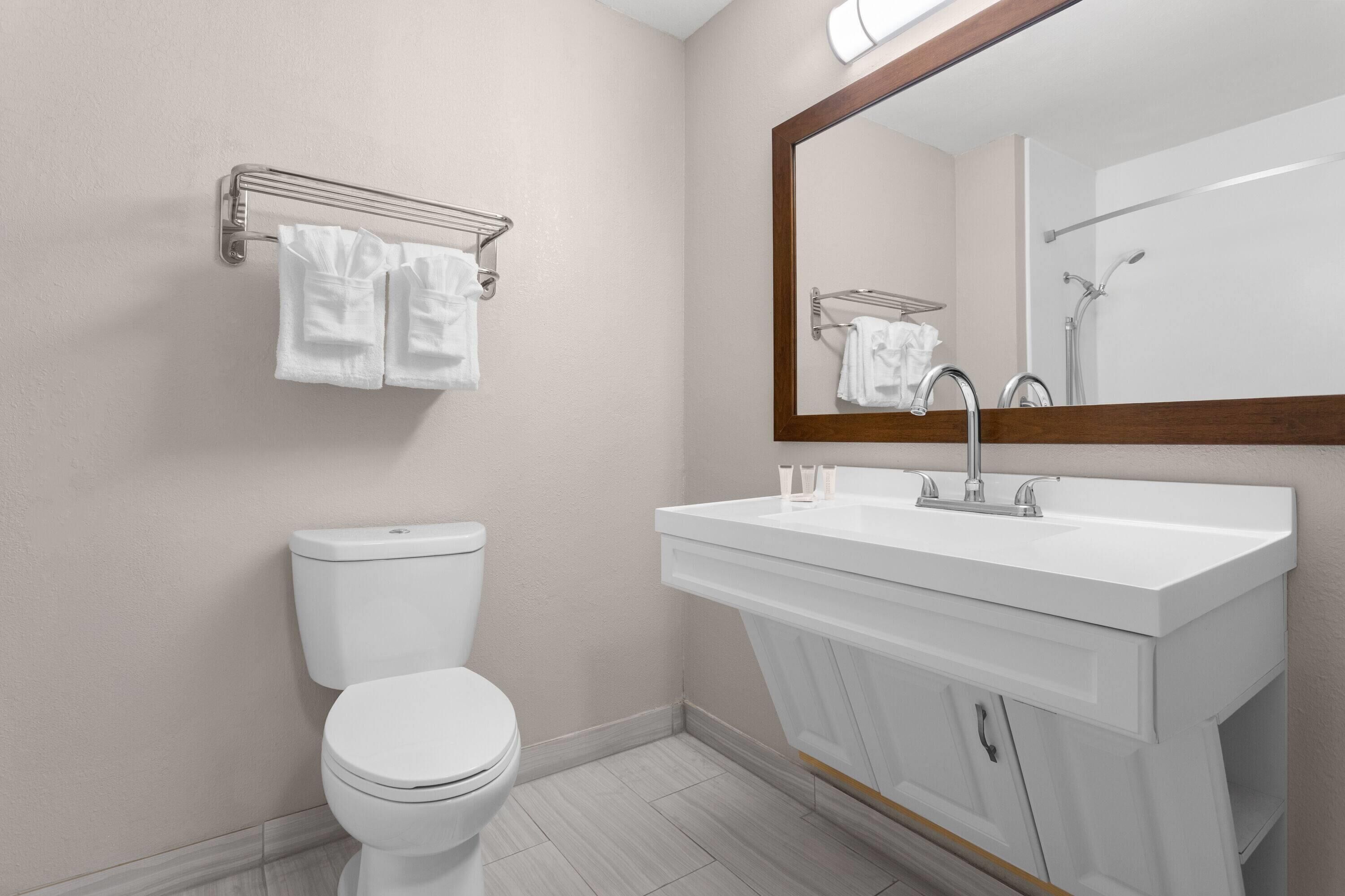 Un baño moderno con inodoro, lavabo y espejo.