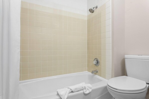 Un baño con bañera, inodoro y paredes de azulejos.