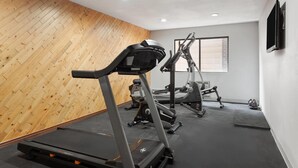 Une salle de sport équipée de tapis de course, de vélos elliptiques et d’appareils de musculation.