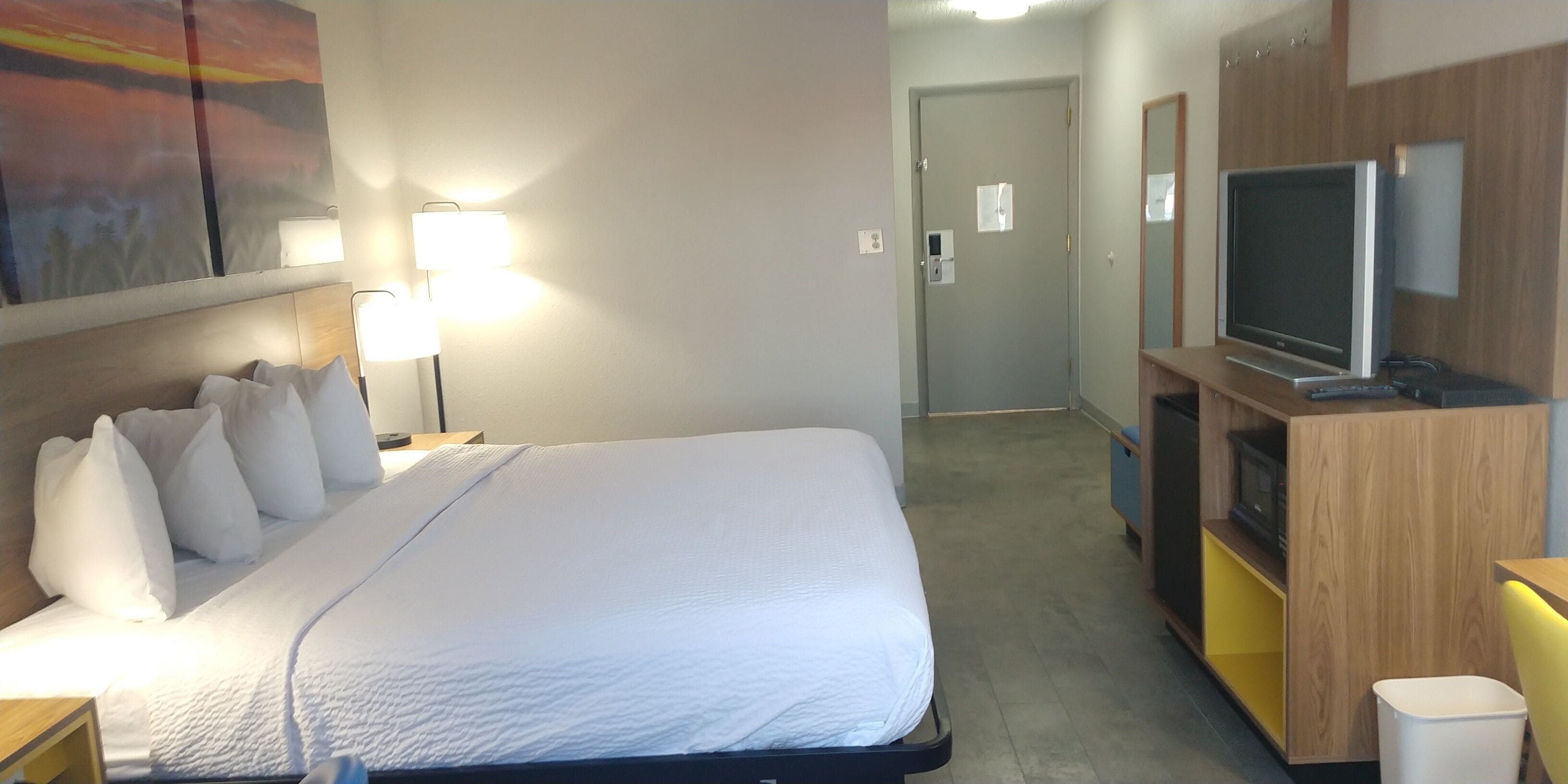 A hotel room with a bed, a TV, a desk, and a lamp.