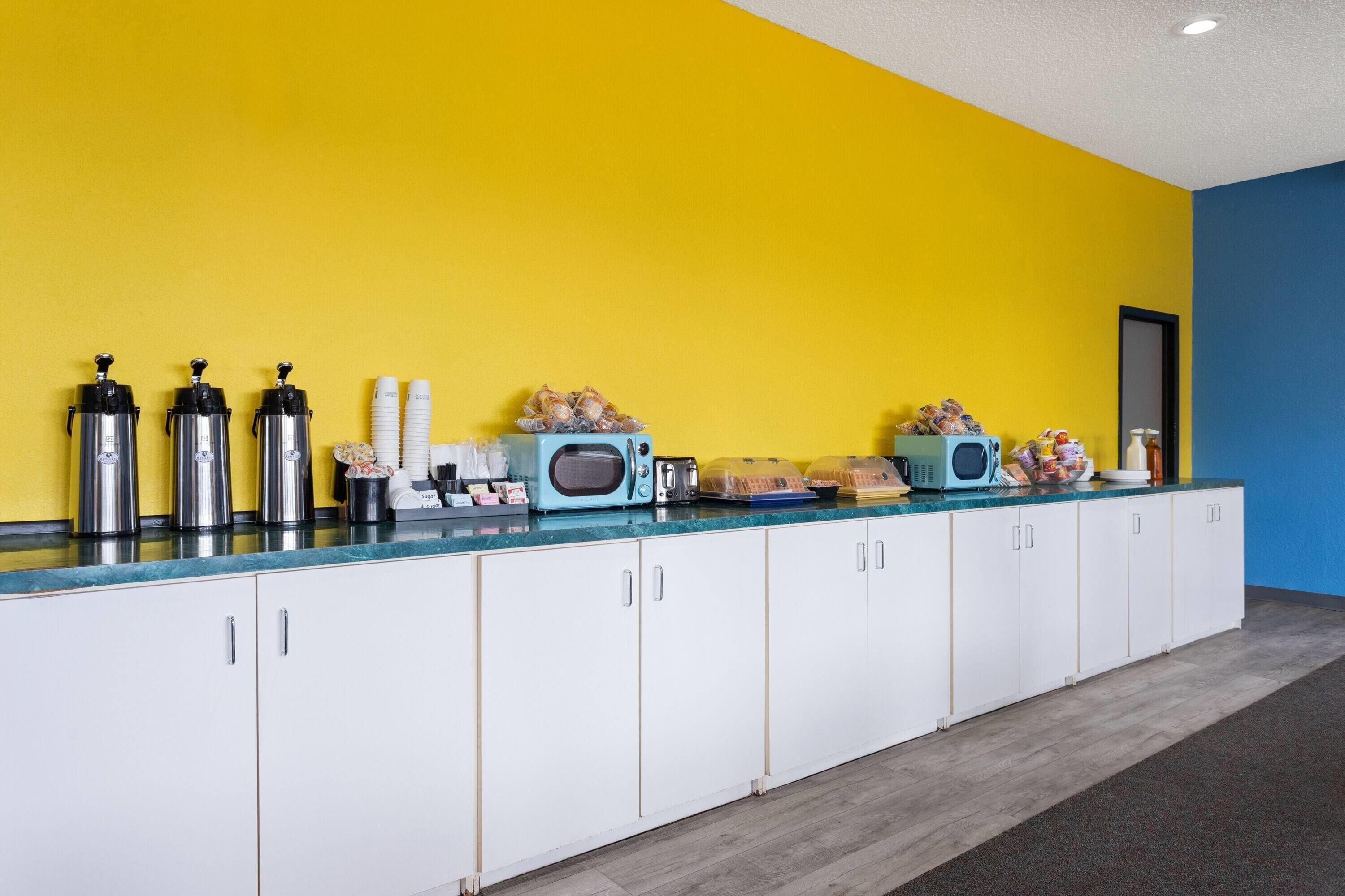 Una cocina con armarios blancos, una pared amarilla y una pared azul.