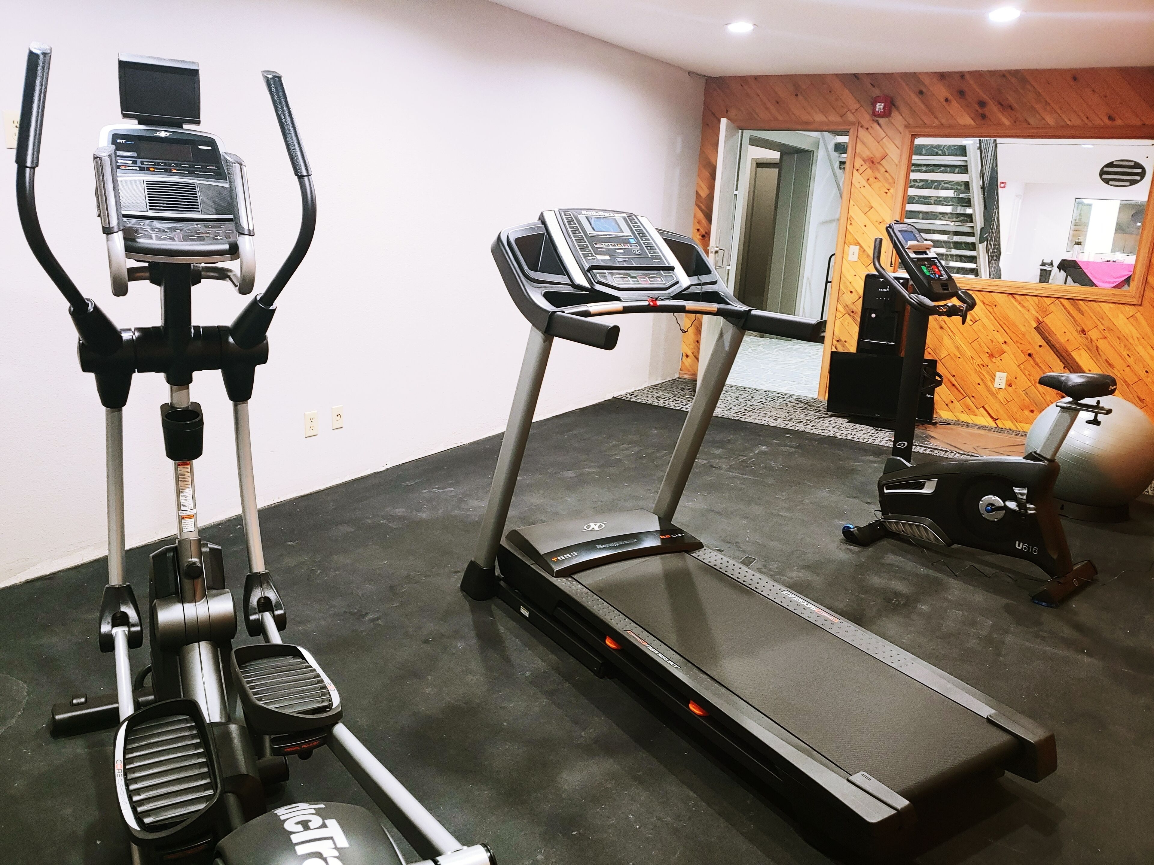 A gym with an elliptical, a treadmill, and a stationary bike.