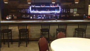 Un espace bar avec un comptoir, plusieurs chaises et une table ronde.