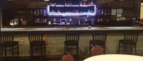 A bar area with a counter, several chairs, and a round table.