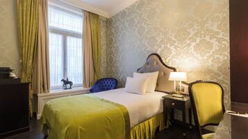 A hotel room with a bed, a desk, a chair, and a window with curtains.