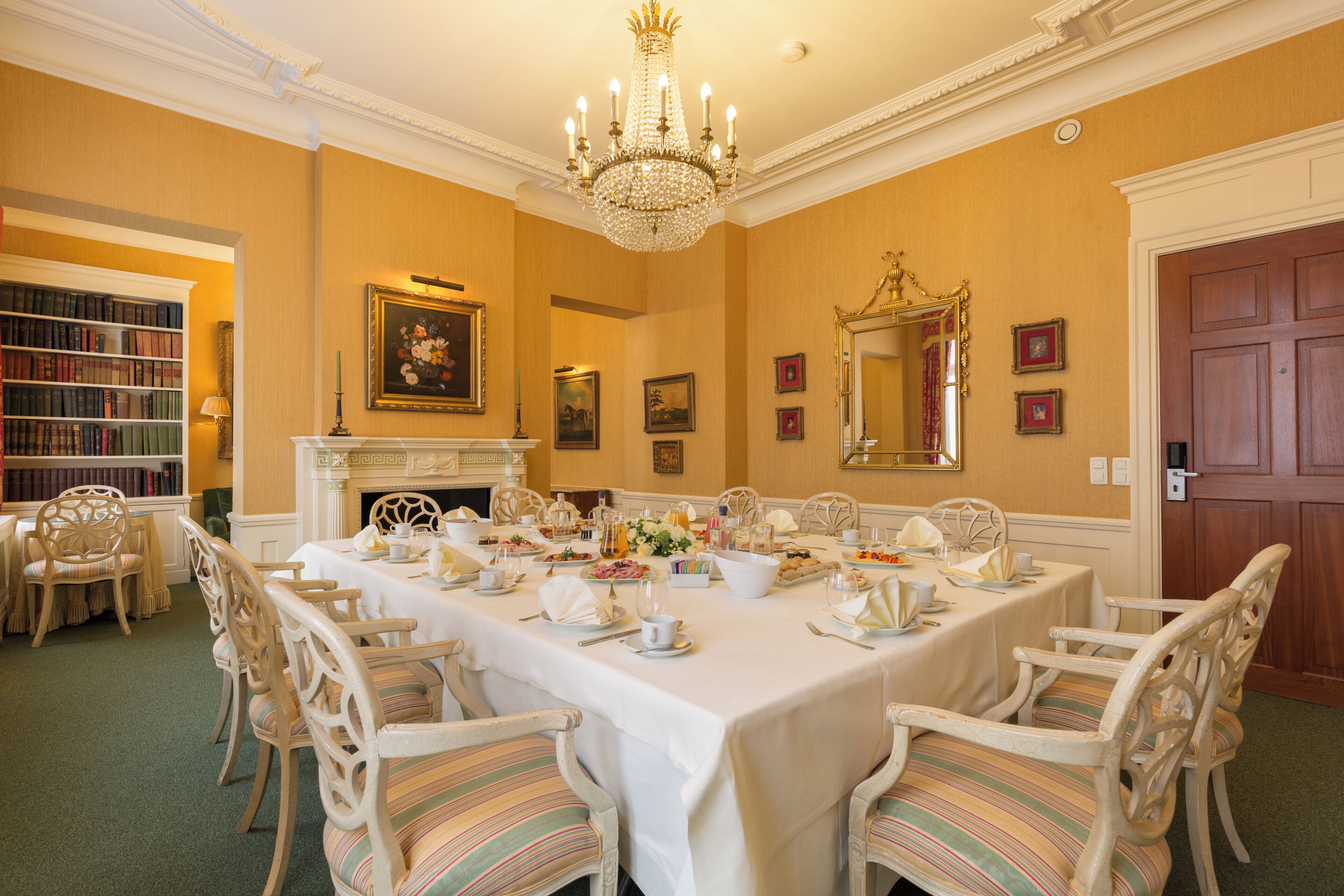 Un comedor formal con una larga mesa dispuesta para una comida, rodeada de sillas ornamentales.
