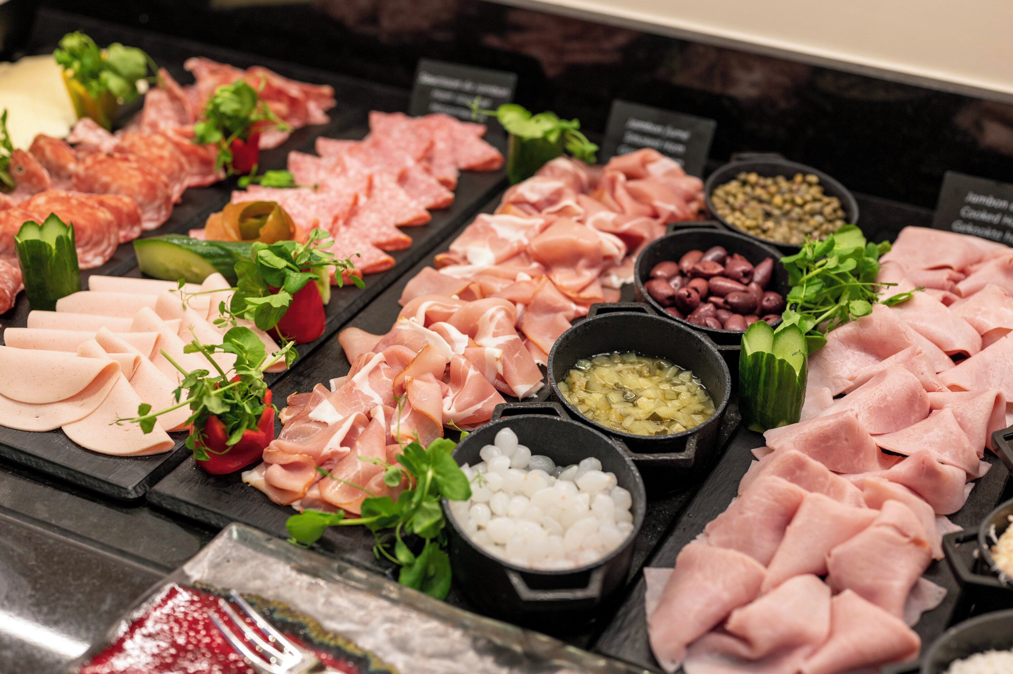 A variety of meats and garnishes on a display board.