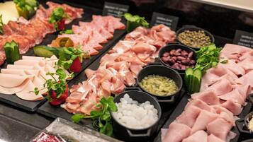 A variety of meats and garnishes on a display board.