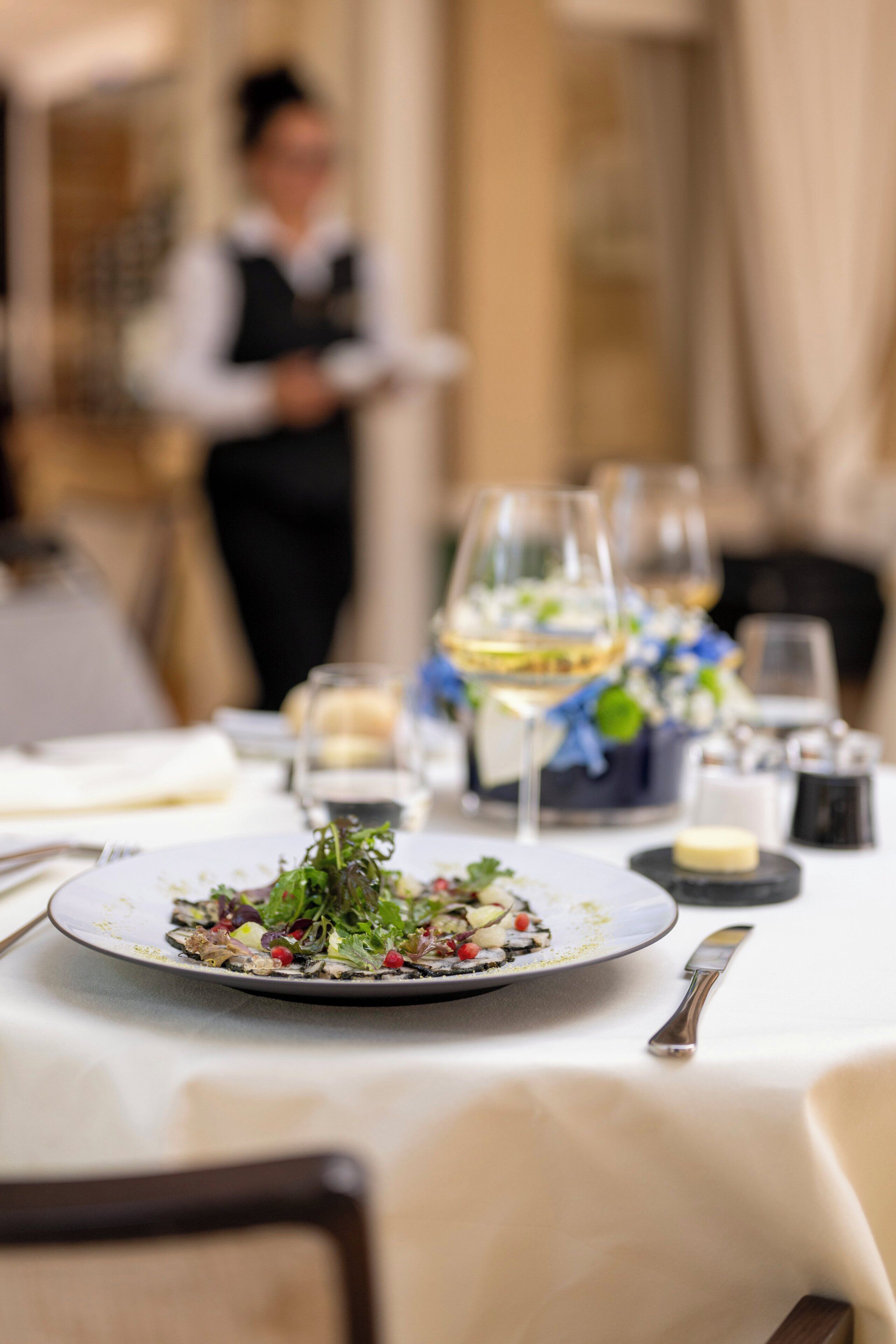 Une table à manger dressée avec une assiette de nourriture, des verres à vin et des couverts.
