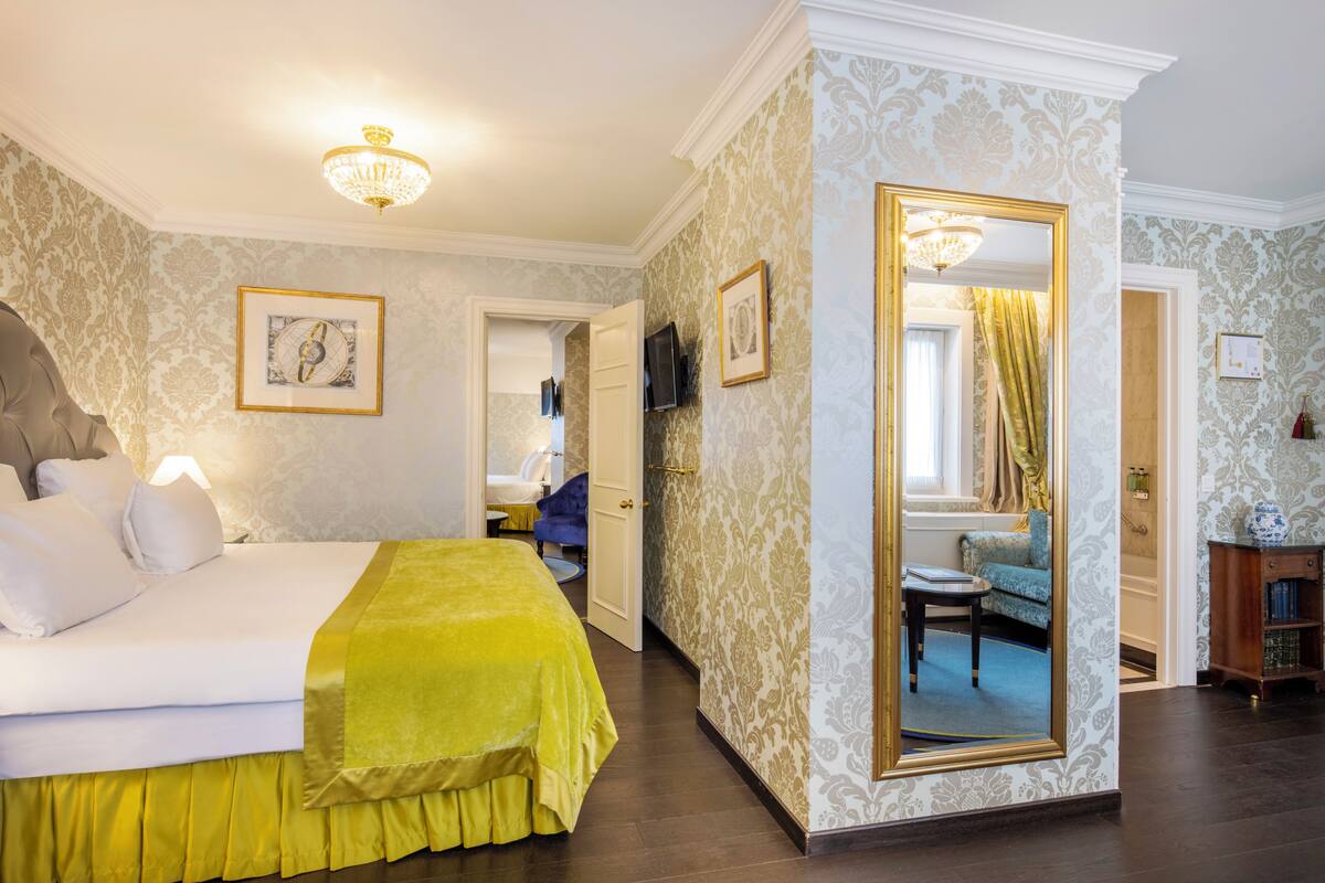 Hotellihuone, jossa on sänky, peili, televisio ja pieni pöytä.