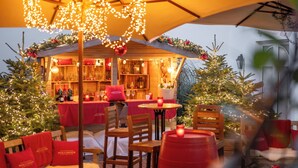 Ein Sitzbereich im Freien mit Tischen und Stühlen, geschmückt mit Weihnachtsbeleuchtung und einem Weihnachtsbaum.