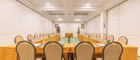 Un salón de conferencias con una larga mesa, varias sillas y suelo alfombrado.
