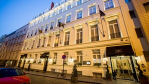 Ein mehrstöckiges Hotel im klassischen europäischen Stil, mit einheitlichen Fenstern und Balkonen sowie einem gut beleuchteten Eingang.
