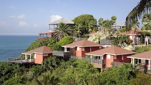 A coastal residential area with houses featuring red roofs and balconies, surrounded by lush greenery and overlooking the sea. - La Toubana Hôtel & Spa (Sainte-Anne)