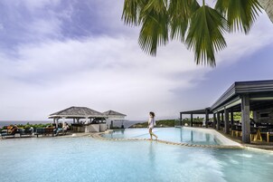Una piscina al aire libre, sombrillas, sillones reclinables de piscina