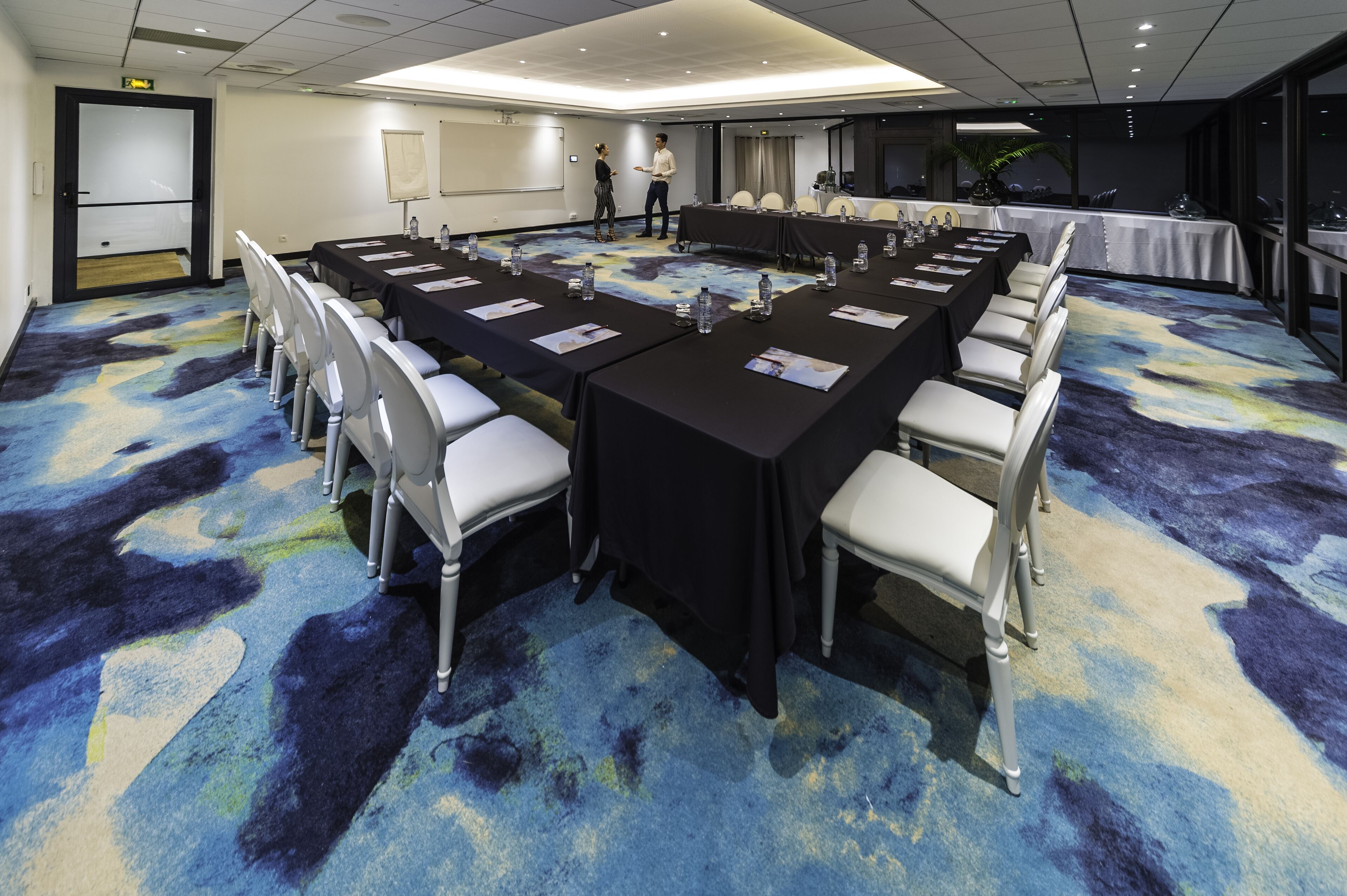 A conference room with a long table, chairs, and a carpeted floor.