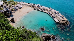 A beach with clear turquoise water, a wooden jetty, and lounge chairs. - La Toubana Hôtel & Spa (Sainte-Anne)