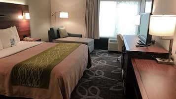 Une chambre d’hôtel avec deux lits, un bureau, une chaise, une télévision et une fenêtre avec des rideaux.