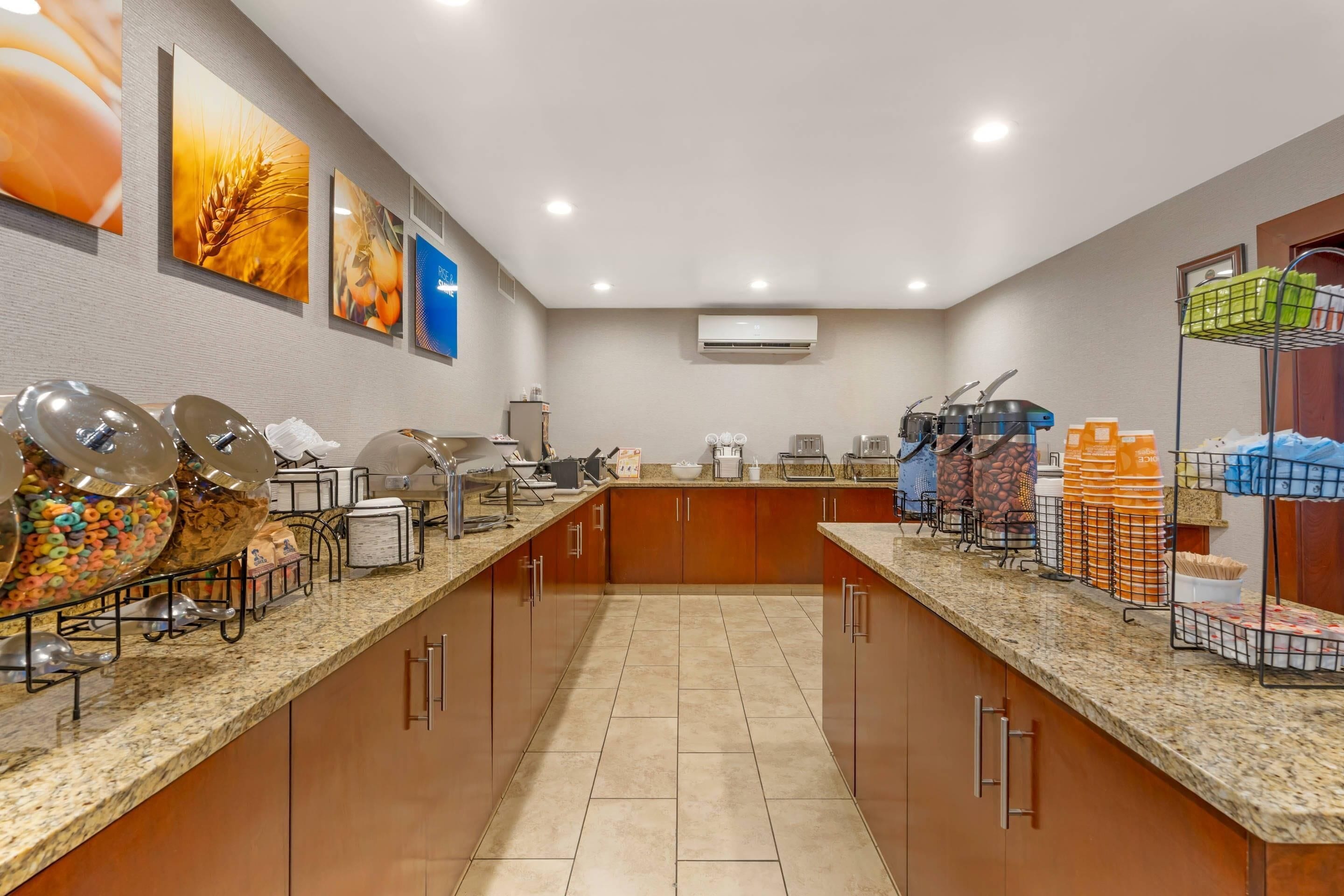 A hotel kitchen with granite countertops, stainless steel appliances, and a variety of food items and utensils.
