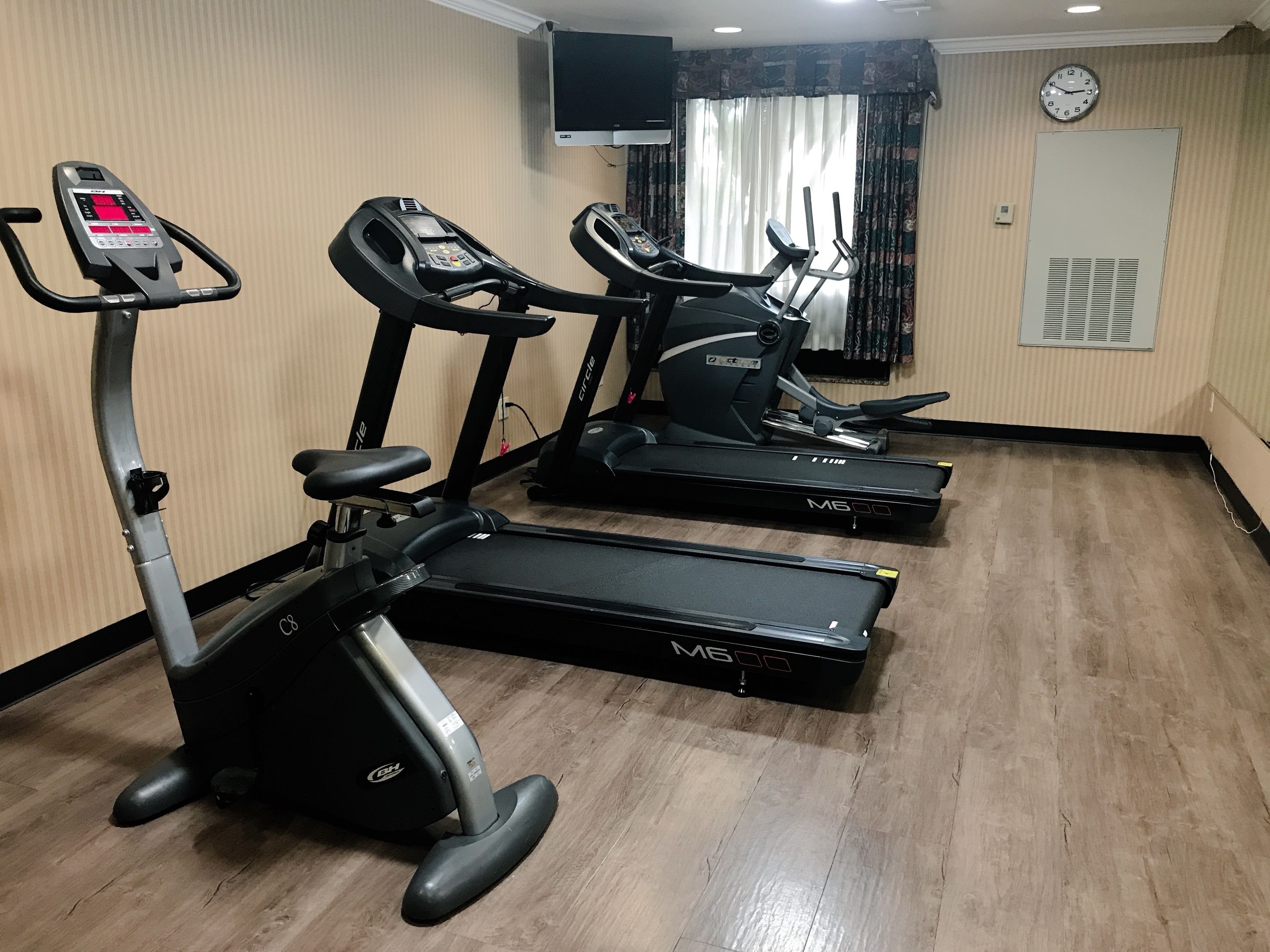 Un gimnasio con cintas de correr, una bicicleta estática y una máquina de remo.