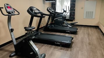 Un gimnasio con cintas de correr, una bicicleta estática y una máquina de remo.