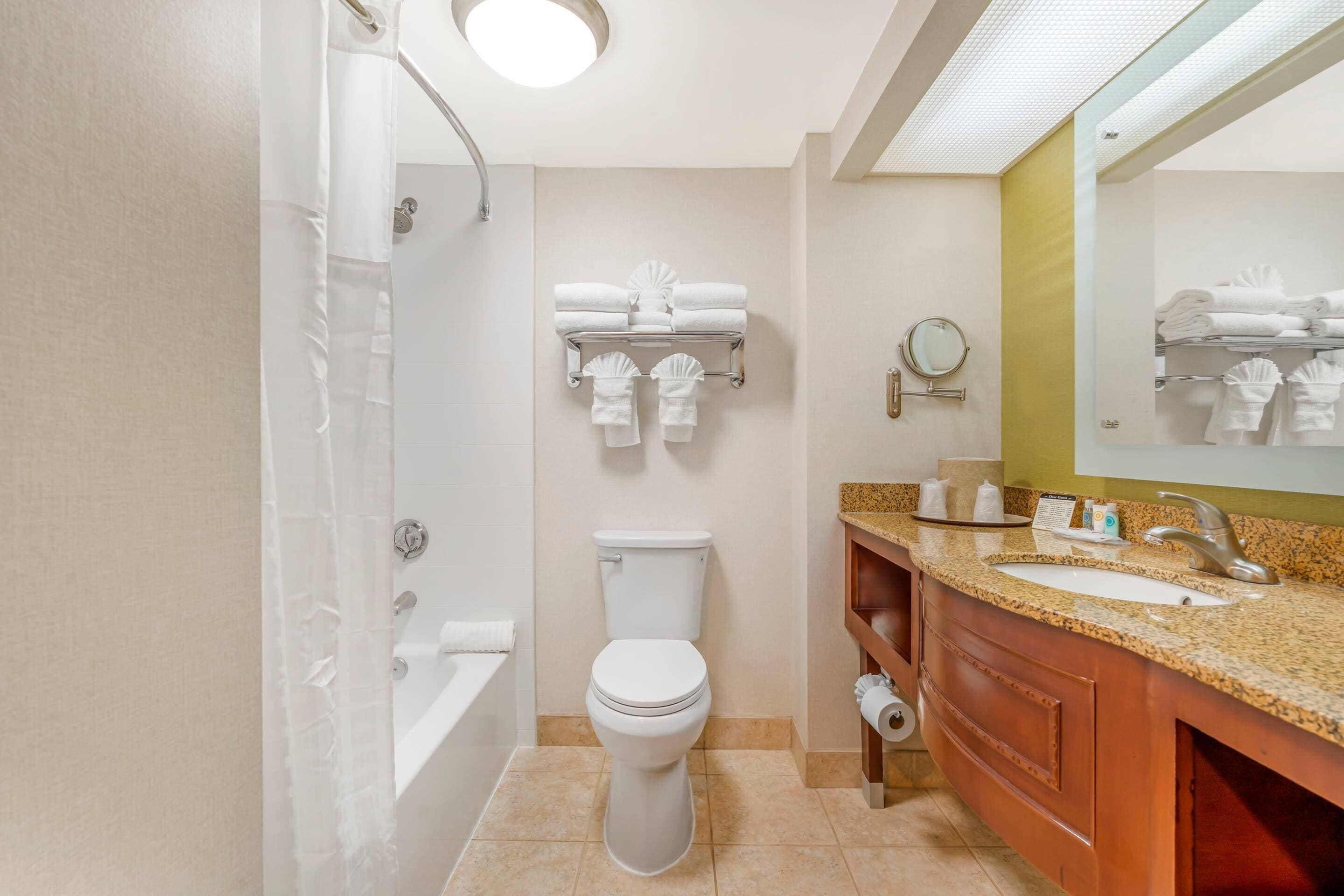 A modern bathroom with a bathtub, toilet, and vanity with a sink and mirror.