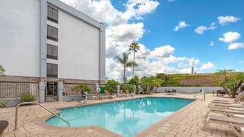 Una piscina al aire libre, sombrillas, sillones reclinables de piscina