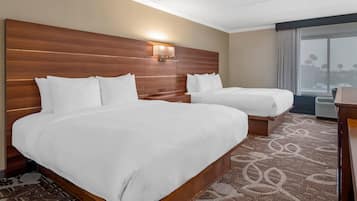 Une chambre d’hôtel avec deux lits, une tête de lit en bois, une lampe fixée au mur et une moquette à motifs.