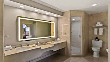 Un baño moderno con un espejo grande, dos lavamanos, una ducha y un inodoro.
