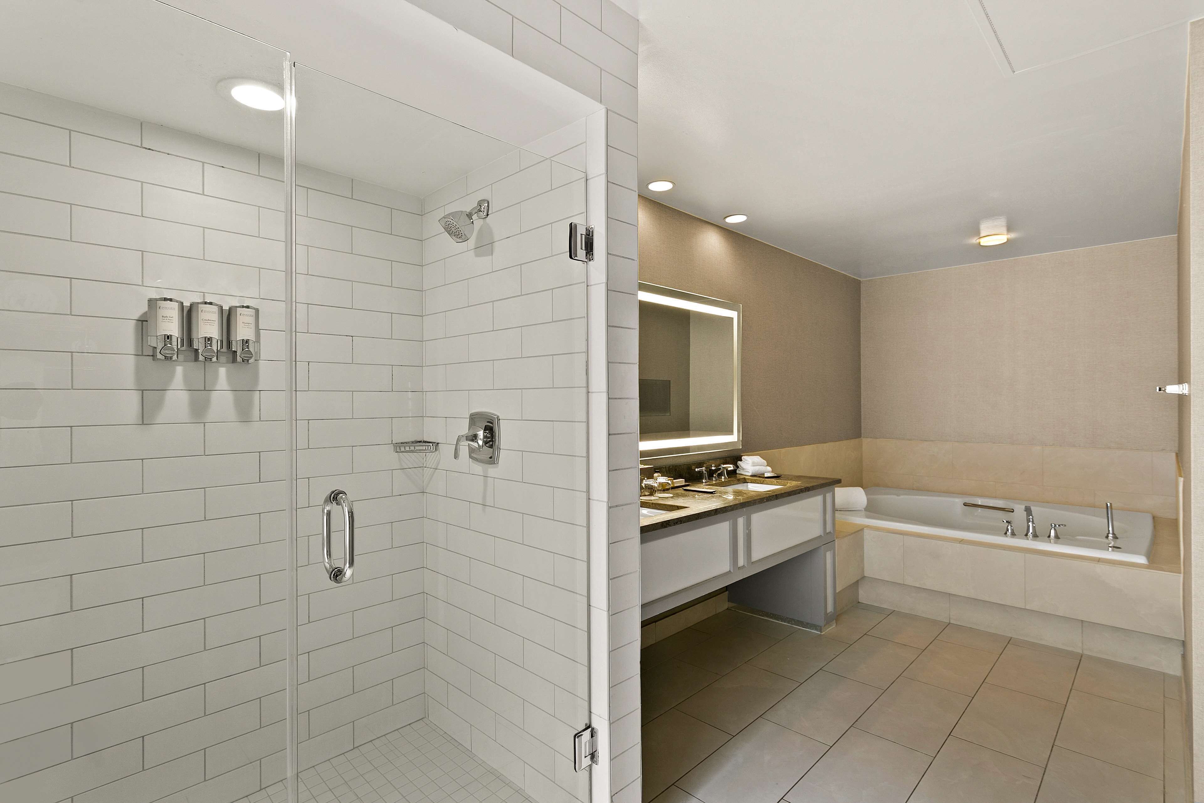 Un bagno moderno con doccia vetro, vasca da bagno ampia e un mobile lavabo con specchio.