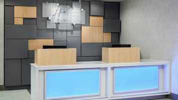 A reception desk with a modern design, featuring a combination of wood and grey panels, and illuminated blue panels on the front.