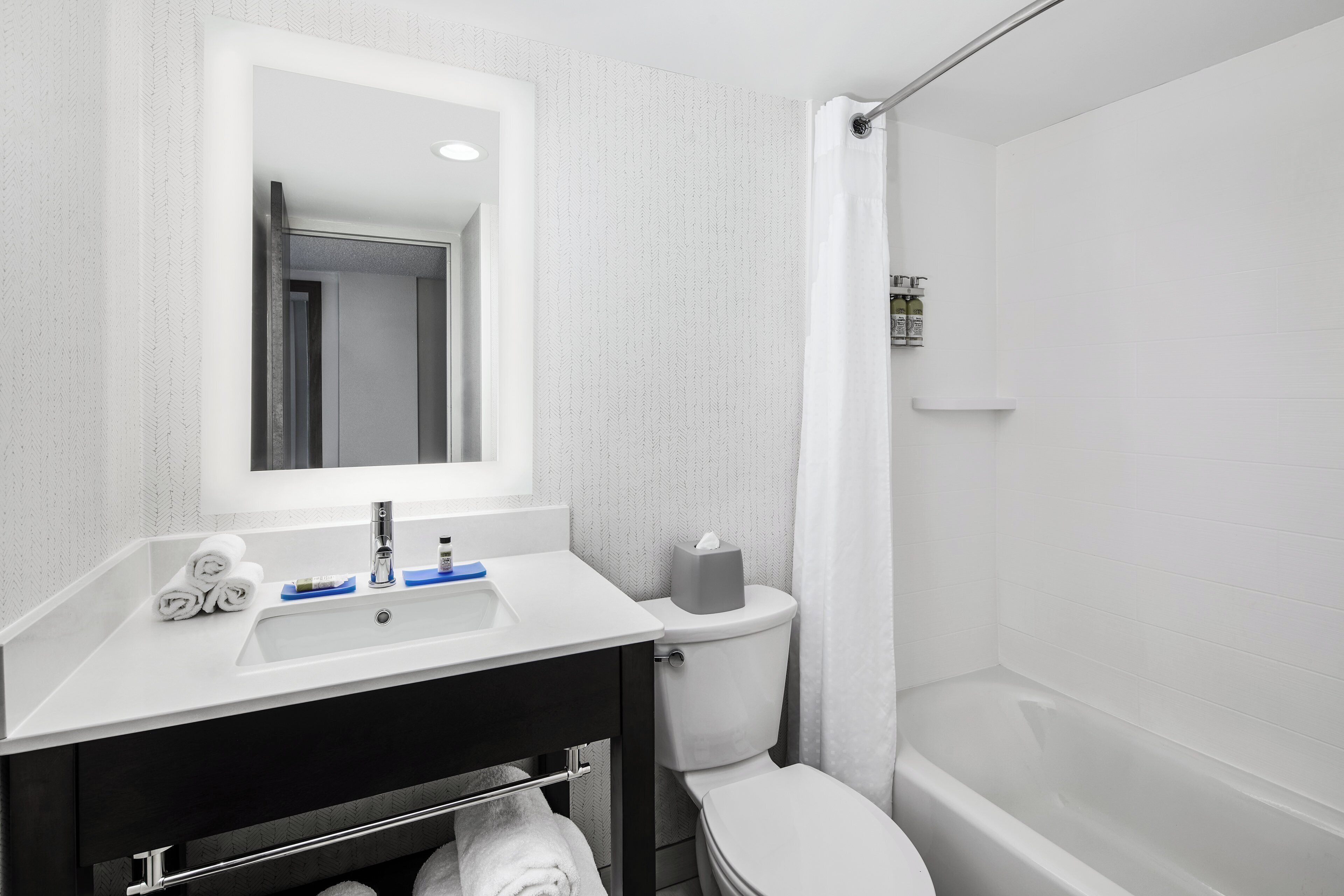 A bathroom with a white sink, mirror, and toilet.