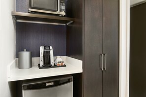 A compact kitchenette with a microwave, coffee maker, and a small refrigerator.