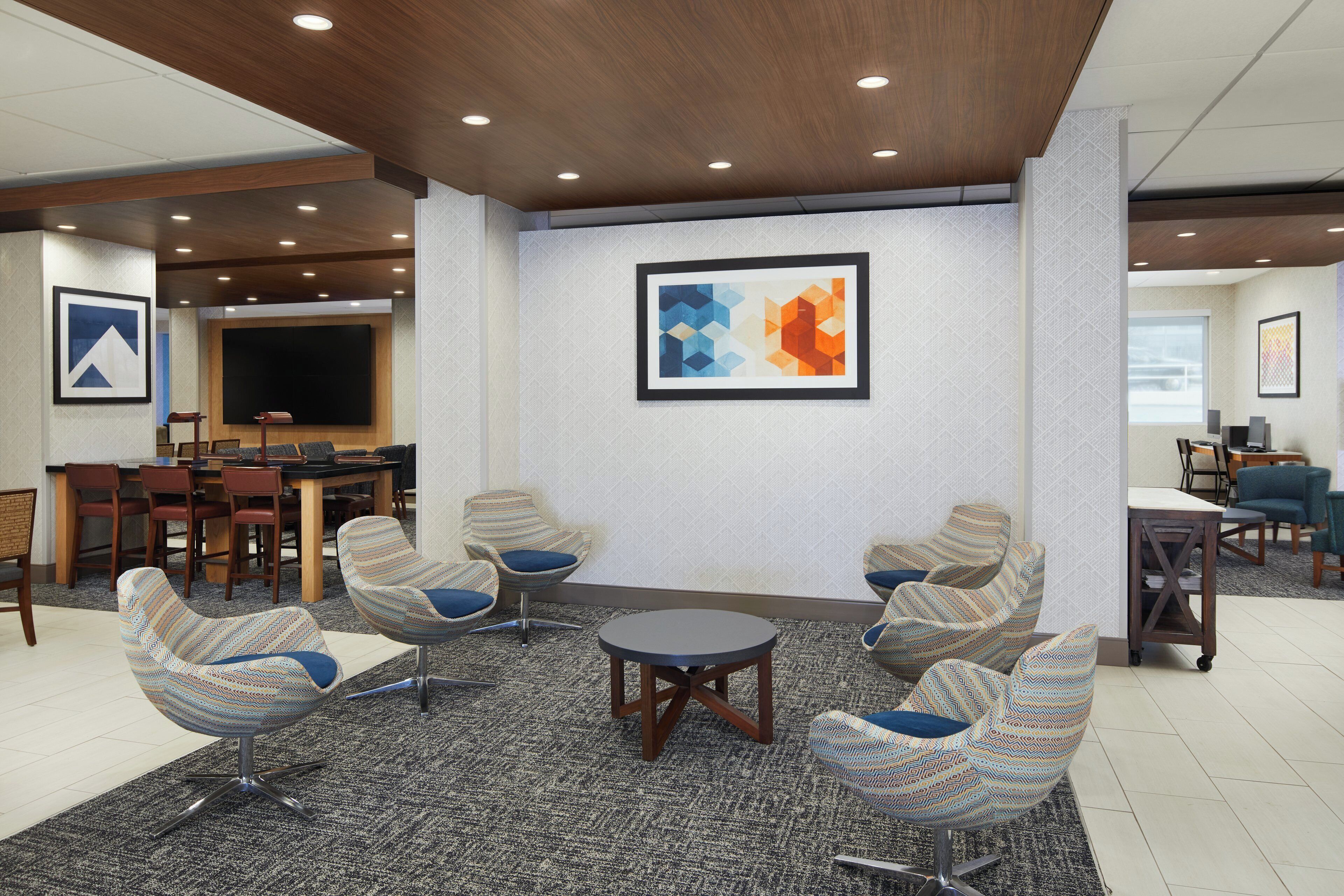 A modern lounge area with a large flat-screen TV, comfortable seating, and a patterned carpet.
