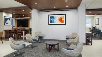A modern lounge area with a large flat-screen TV, comfortable seating, and a patterned carpet.