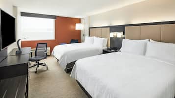 Habitació d'hotel amb dos llits, una taula, una cadira, una televisió i una finestra.