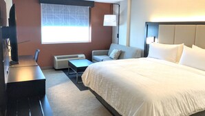 A hotel room with a bed, a desk, a chair, a small table, a heater, a window with a view, and a TV. - Holiday Inn Express Richmond - Midtown by IHG (Richmond)